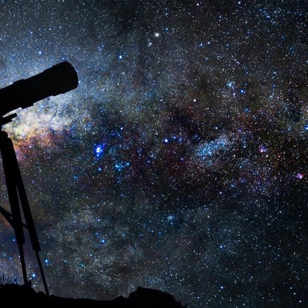 a telescope is silhouetted against a starry sky